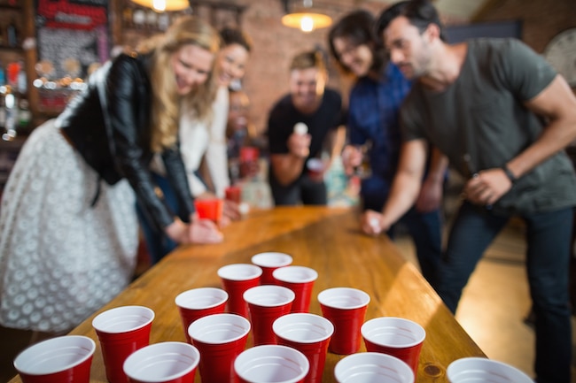 Friends enjoying beer pong game in bar